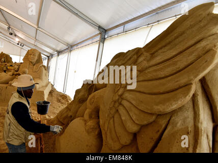 Elstal, Germania. Xvii Apr, 2015. Bob Attiso dal Togo opere sulla sua la scultura di sabbia in Elstal, Germania, 17 aprile 2015. Utilizzando 1.100 tonnellate di sabbia, 20 artisti internazionali di portare le loro nozioni del mondo africano per la vita al primo Sandworld Berlino. La mostra si apre il 01 maggio 2015 in Karls adventure village. Foto: BERND SETTNIK/ZB/dpa/Alamy Live News Foto Stock