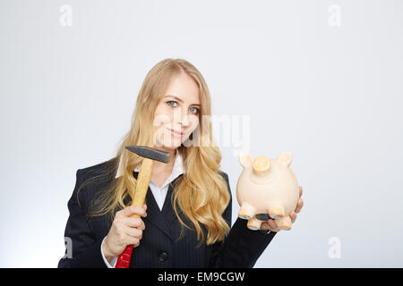 Grave imprenditrice tenendo un piggy-bank e un martello Foto Stock