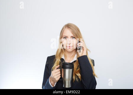 Bella imprenditrice caucasici di parlare al telefono tenendo un caffè Foto Stock