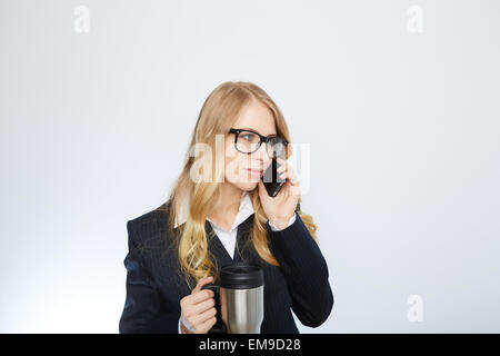 Bella imprenditrice caucasici di parlare al telefono tenendo un caffè Foto Stock