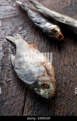 Salato a secco fiume pesce è su un marrone di sfondo di legno Foto Stock