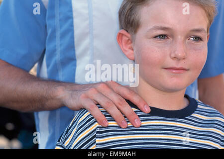All'esterno ritratto di ragazzo di mano del padre sulla spalla Foto Stock