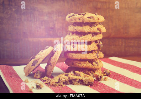 Pila di biscotti con scaglie di cioccolato sulla rossa e bianca igienico contro un legno scuro sfondo, con applicata in stile vintage filtro Foto Stock