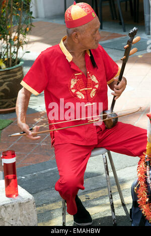 Uomo cinese in costume tradizionale riproduzione di un Erhu strumenti musicali in Singapore Chinatown Foto Stock