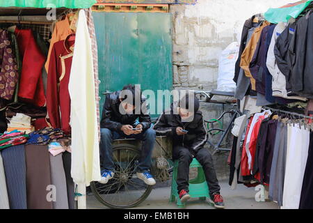 LHASA, in Tibet, Cina - 19 ottobre: Non tibetani persone han ragazzi giocare con e-dispositivi di gioco-parte posteriore di street shop-Lhasa-Tibt Foto Stock