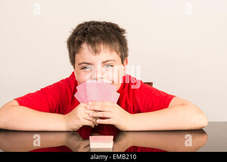 Ritratto di giovane ragazzo giocando a carte malizia Foto Stock