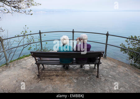 Una coppia di anziani seduti su una panchina a guardare il mare Foto Stock