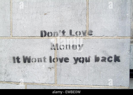 Graffiti ' non amano il denaro si preferirà love you back' su un muro di pietra di un edificio della banca in Dublino Irlanda Regno Unito Europa Foto Stock