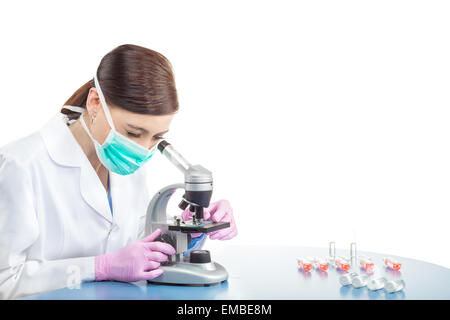 Medico donna o ricercatore scientifico in maschera mediante microscopio in un laboratorio, spazio per il testo. Foto Stock
