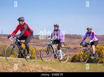 Due maschi e una femmina ciclisti competere nella nuova foresta dimenare evento sportivo su una soleggiata domenica di primavera Foto Stock