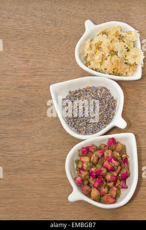 Assortimento di fiori secchi tè nella ciotola bianco,bocciolo di rosa, lavanda e fiore del Crisantemo tea Foto Stock