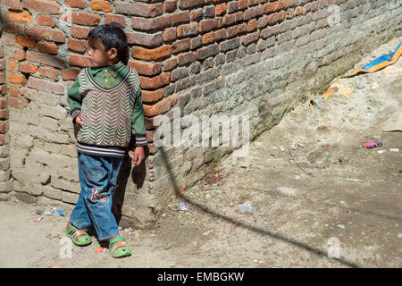 Un giovane ragazzo è appoggiata contro una parete di Kathmandu Foto Stock