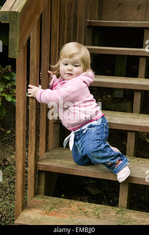 17 mesi toddler cercando di scendere al di fuori delle scale, incerta della sua capacità di farlo, Issaquah, Washington, Stati Uniti d'America Foto Stock