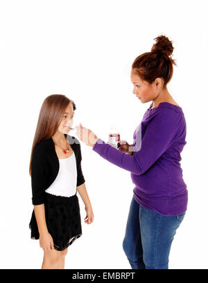 Una bella ragazza con i capelli lunghi e ottenere alcune medicine da sua madre, isolato per sfondo bianco. Foto Stock