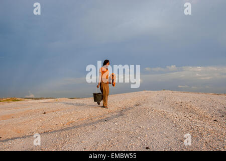 Un minatore d'oro in piccola scala che cammina sul paesaggio lunare nel sito di estrazione dell'oro di Galangan, Kalimantan centrale, Indonesia. Foto Stock