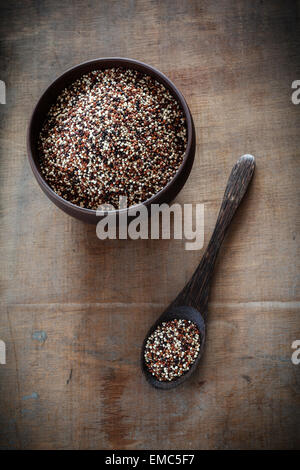 Il cucchiaio di legno e la tazza di quinoa crudo grani tricolore Foto Stock