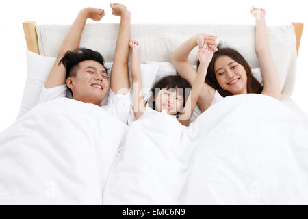 La felicità di una famiglia di tre persone nel letto della camera da letto si è svegliato Foto Stock