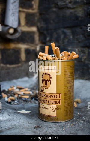 Un vecchio caffè turco contenitore pieno di usato mozziconi di sigaretta. Foto Stock