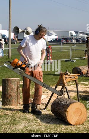 L'uomo utilizzando una motosega per scolpire statue con tronchi di alberi Foto Stock