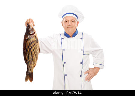 Maschio maturo cuoco in un pulito bianco uniforme tenendo un fresco pesce crudo isolati su sfondo bianco Foto Stock