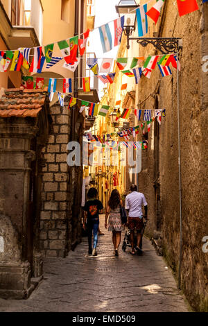 Una famiglia a piedi attraverso i vicoli in l'artista della zona di Sorrento. I vicoli sono decorate con le bandiere di molte nazionalità. Foto Stock