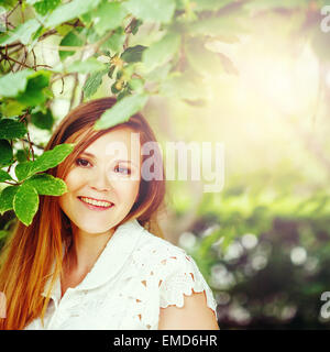 Bellissimi capelli rossi Donna sorridente contro la natura sfondo verde. Estate relax. Nei toni dell'immagine con colori ciano. Foto Stock