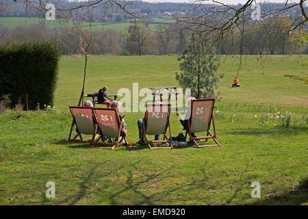 Persone sedersi in sedie a sdraio e godersi il sole a Emmetts Giardini in Kent Foto Stock