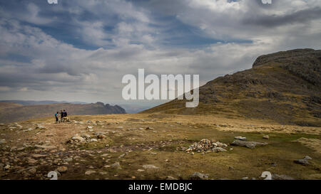 Walkers lavorando fuori il loro percorso presso ESK Hause con il Langdales in background e Esk Pike a destra Foto Stock