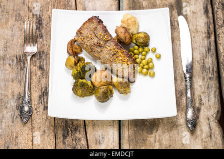 Il menu del ristorante sfondo. Tritare arrosto di manzo con verdure su piastra bianca con servita argenteria Foto Stock