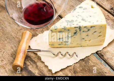 Chiudere l immagine del pezzo di formaggio blu con wineglass ribaltata e cavatappi su uno sfondo di legno Foto Stock