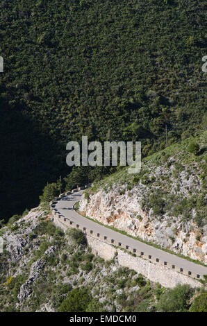 Avvolgimento stretto lastricata strada di montagna con basse barriere di pietra, Ojen, Andalusia, Spagna. Foto Stock