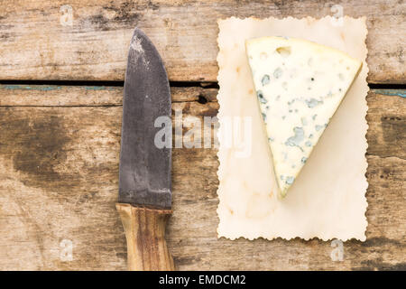 Formaggio blu sfondo con copyspace. Pezzo di formaggio con il vecchio coltello su un tavolo di legno Foto Stock
