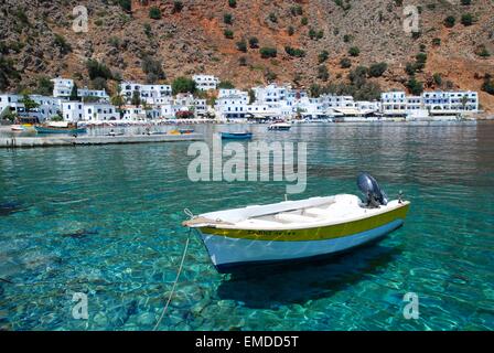 Piccola barca sulle acque cristalline turchesi del mare nel pittoresco villaggio imbiancato di Loutro, Creta sud-occidentale, Grecia Foto Stock