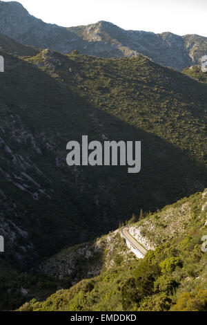 Avvolgimento stretto lastricata strada di montagna con basse barriere di pietra, Ojen, Andalusia, Spagna. Foto Stock