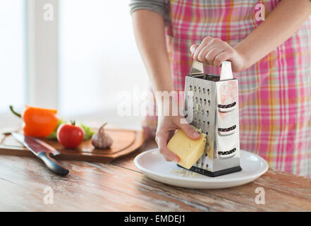 Close up di mani femminili grattugiare il formaggio Foto Stock