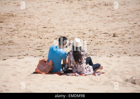 Giovane seduto sulla sabbia a Bournemouth Beach in aprile Foto Stock