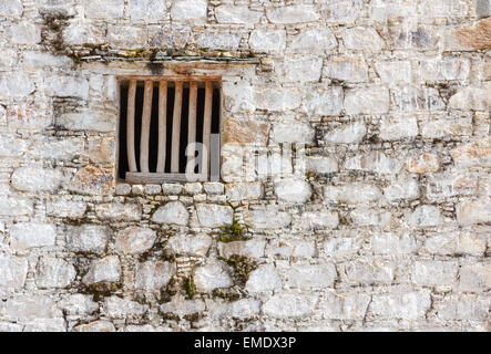 Vecchia Prigione la finestra della cella con barre di legno in un bianco muro di mattoni Foto Stock