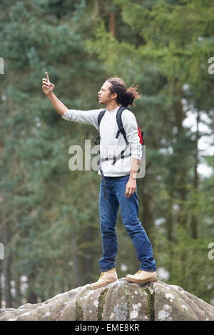 Uomo che utilizza il telefono cellulare mentre passeggiate in campagna Foto Stock