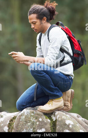 Uomo che utilizza il telefono cellulare mentre passeggiate in campagna Foto Stock