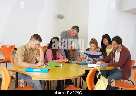 Gli studenti universitari con Tutor utilizzando dispositivi digitali Foto Stock