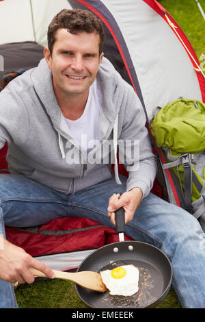 Uomo sulla vacanza in campeggio Uovo di frittura in padella Foto Stock