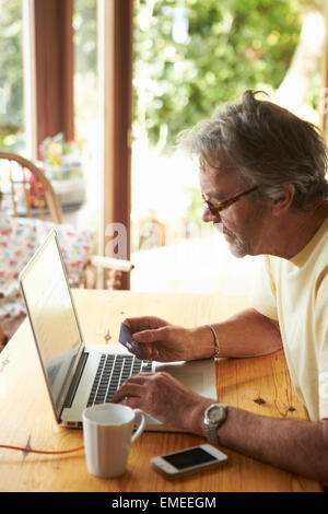 Uomo maturo rendendo acquisto on line con carta di credito Foto Stock