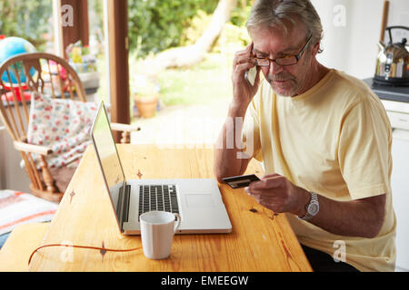 Uomo maturo rendendo acquisto on line con carta di credito Foto Stock