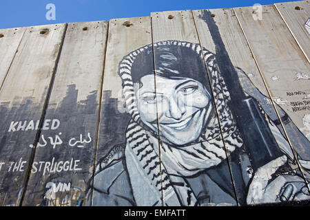 Betlemme, Israele - 6 Marzo 2015: il dettaglio di graffitti sulla barriera di separazione. Donna palestinese con l'arma. Foto Stock
