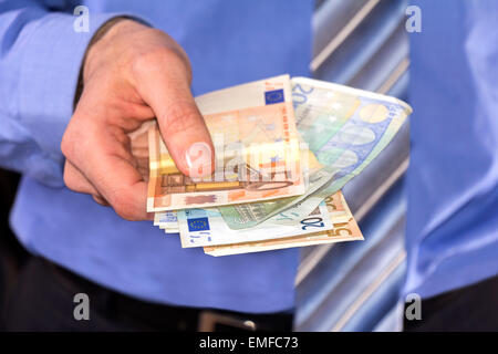 Uomo in una maglietta blu, pagare in euro le banconote Foto Stock