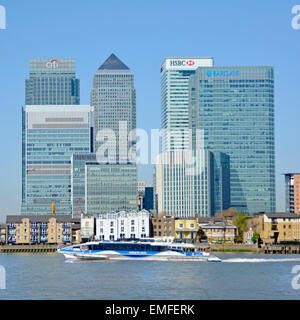 Docklands di Londra Canary Wharf skyline inclusi banche HQ edifici dal fiume con Thames clipper passante Foto Stock