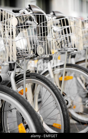 Biciclette da città con cestello anteriore sono visti in un punto di noleggio Foto Stock