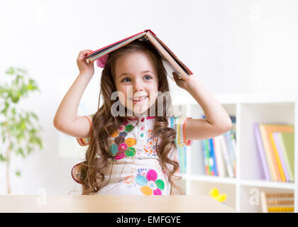 Preschooler kid ragazza con libro sopra la testa Foto Stock