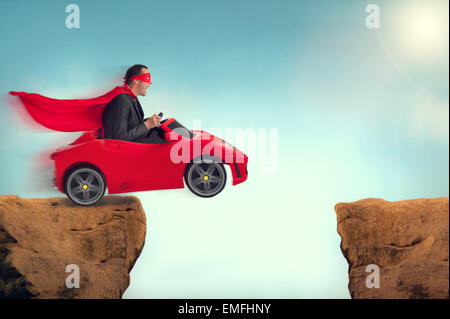 Uomo in un auto rossa saltando un gap burrone sfida Foto Stock