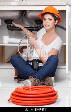 Donna idraulico che fissa la cucina Foto Stock